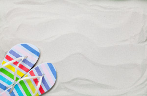 Colorful summer flip flops on white sand.