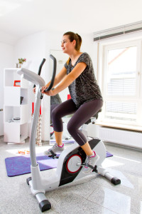 Junge Frau zuhause auf dem Ergometer